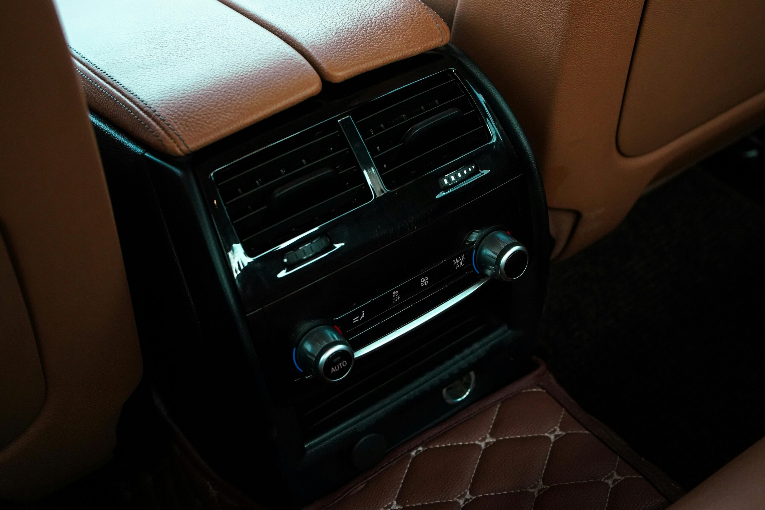 Close-up of a luxury car interior showcasing leather seats and climate control with air conditioning and radio controls.